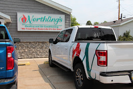 Angled back view of a Nerthling's truck in front of their storefront with a large company name sign on it