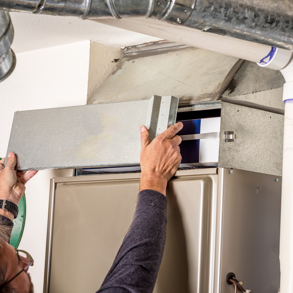 Man moving panel to access furnace filter and replace it