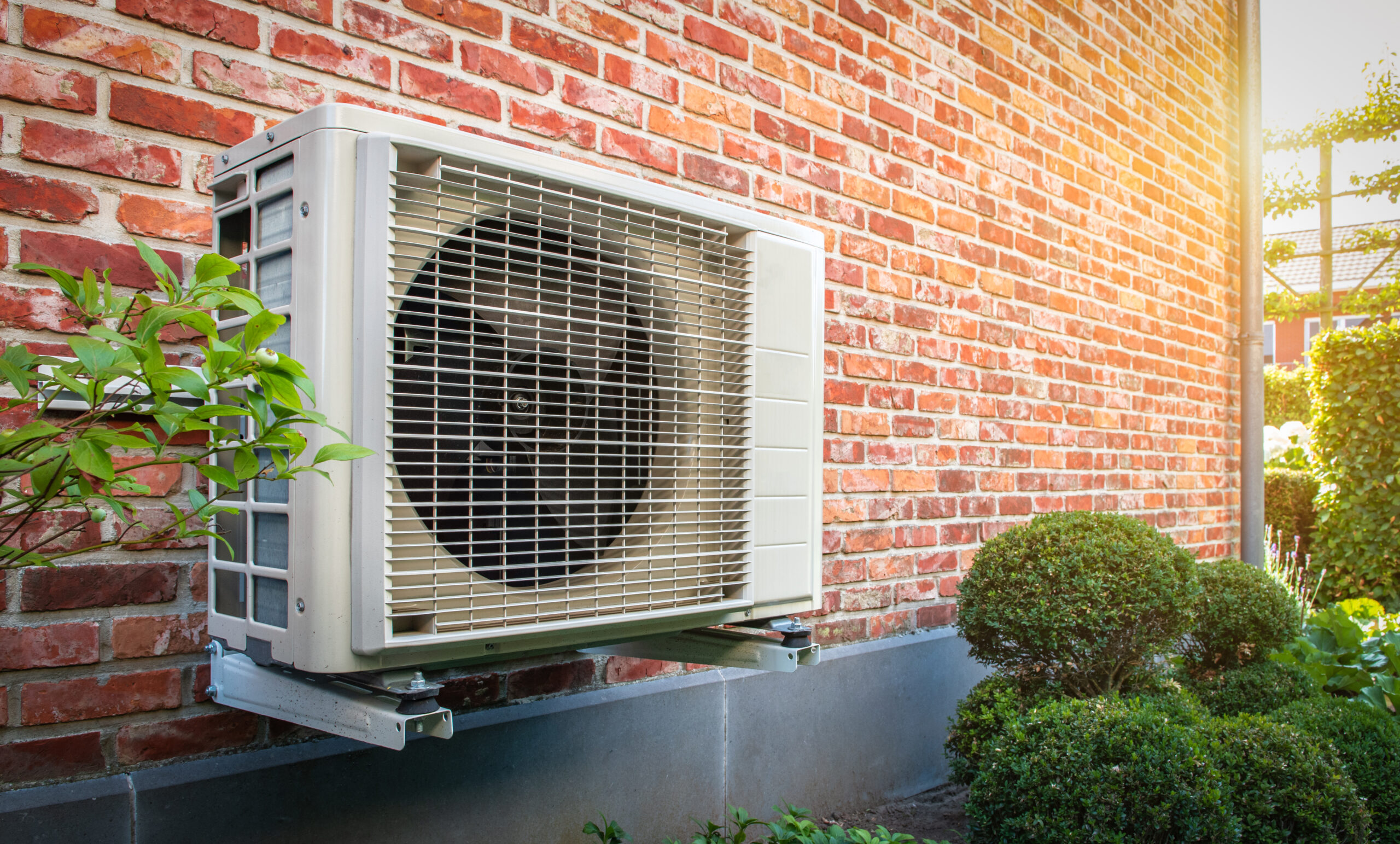 Side view of outdoor energy unit hanging on brick wall of house